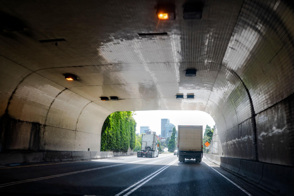 Big rig semi trucks tractors running on the city road through the tunnel