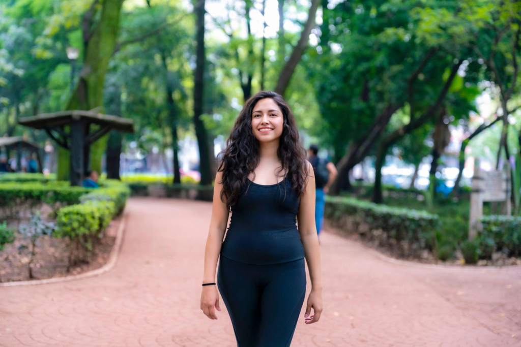 Sporty Latina woman walking along a tree-lined path in Parque México,