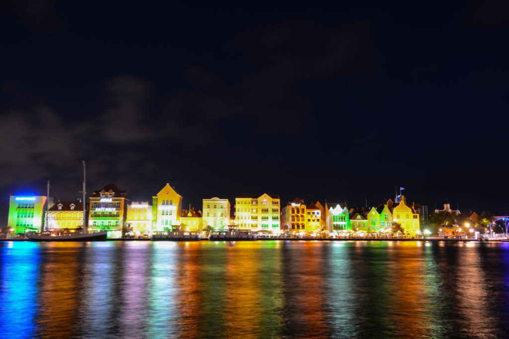 Brightly lit colorful colonial buildings along the Willemstad waterfront at night