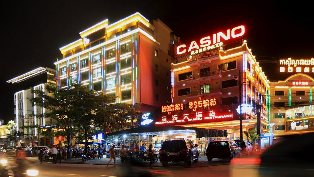 Brightly lit Golden Sand Hotel and Casino building at night with large neon signs in English and Khmer