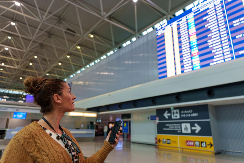 Travelers checking flight information at an airport terminal.