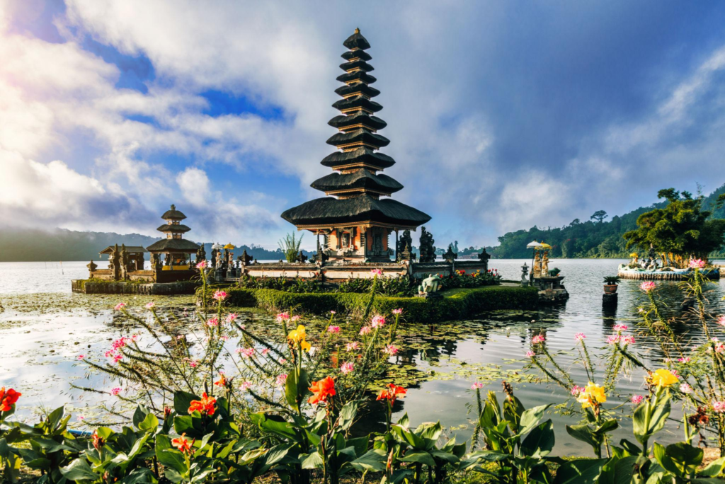 Multi-tiered Balinese water temple on a lake with mountains and clouds in the background