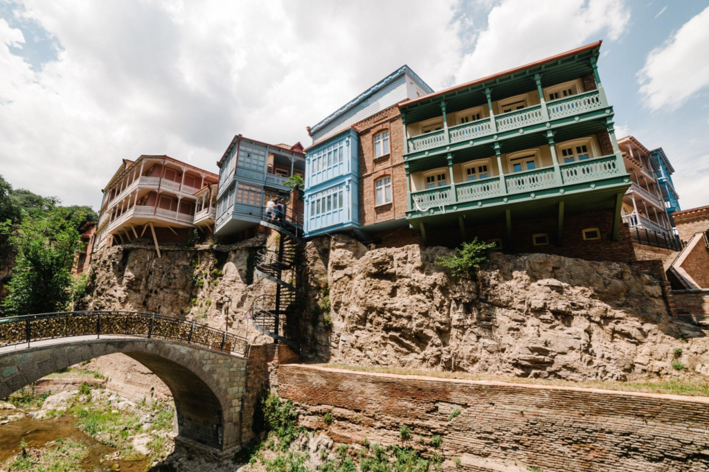 Colorful houses with ornate wooden balconies built into a rocky cliffside in Tbilisi's old town