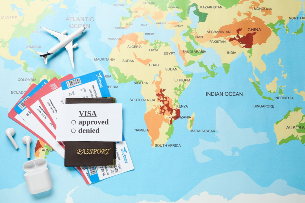 A passport, boarding passes, and a card with visa approved and denied checkboxes on a world map