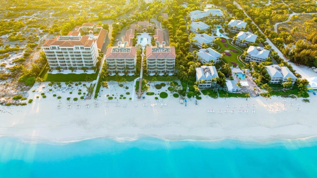 Aerial view of a luxury beachfront resort with turquoise water, white sand, and lush tropical landscaping