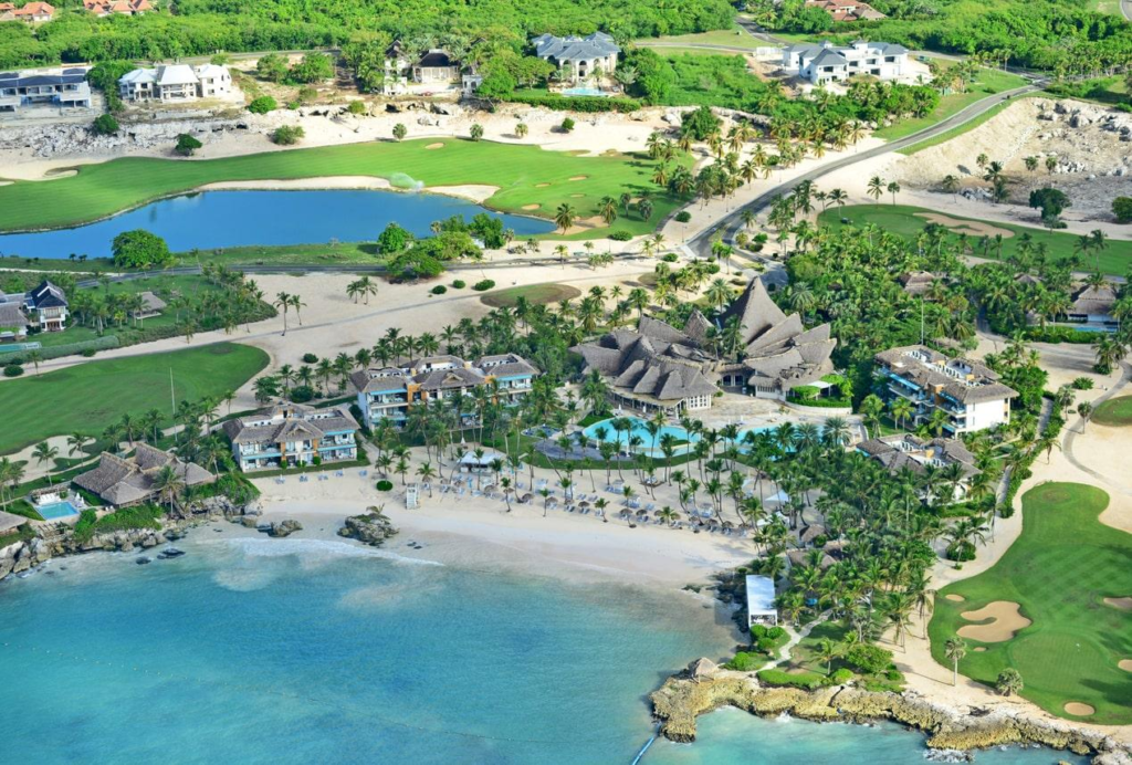 Aerial view of Secrets Cap Cana Resort & Spa showing the beachfront, pool area, and adjacent golf course